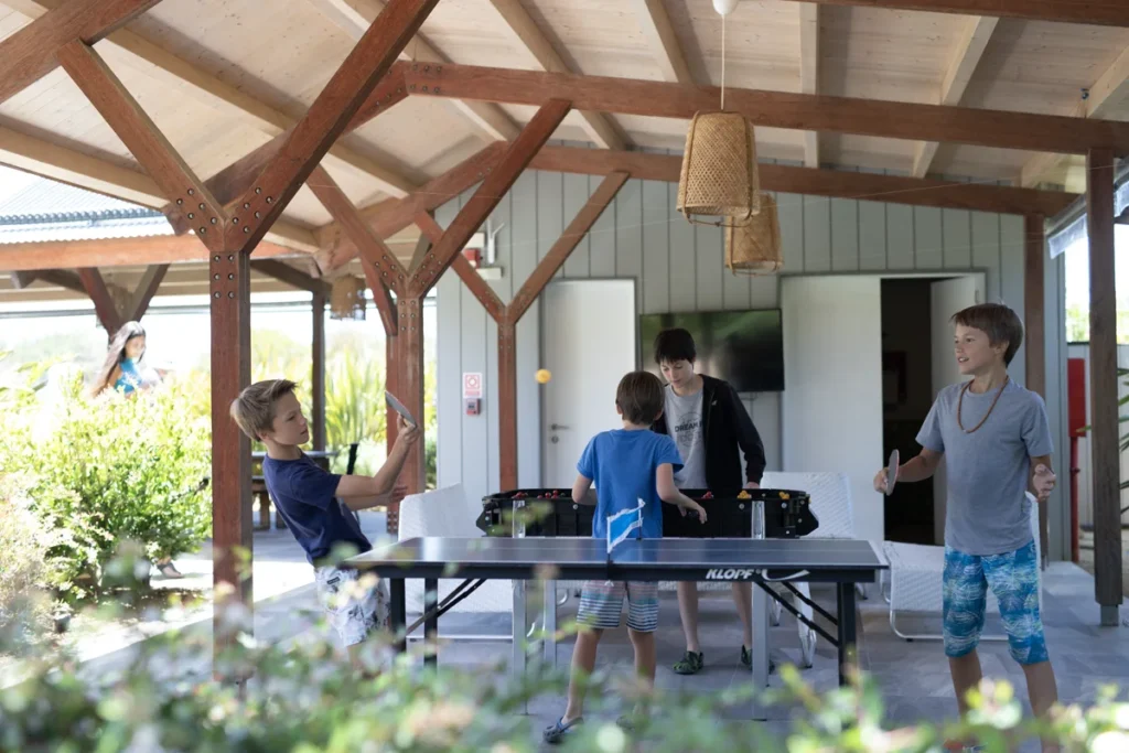Niños jugando al ping pong y metegol en el espacio de juegos de Anastasio House Vilas.